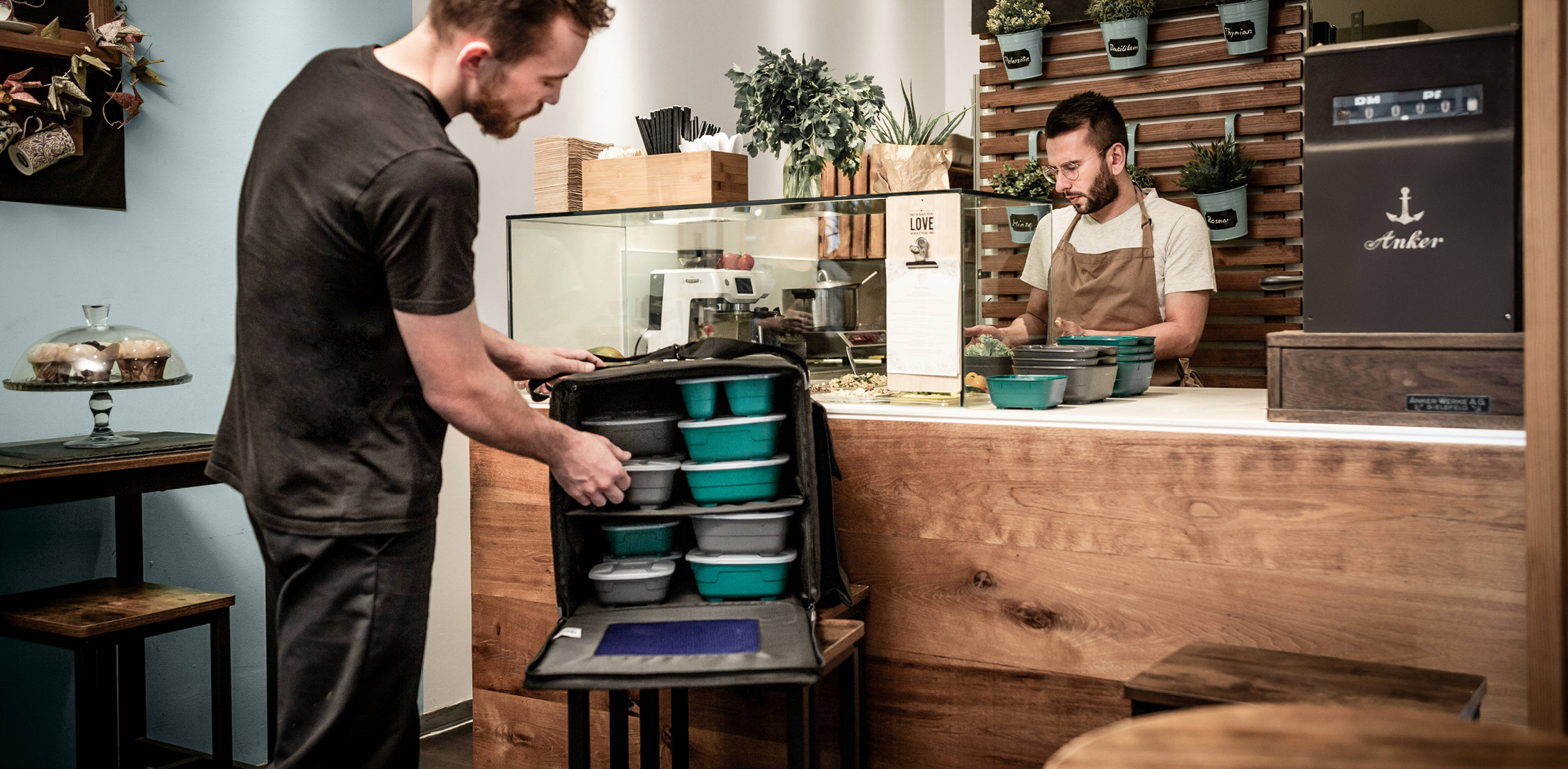 Lieferbote verpackt nachhaltig stapelbare To-Go-Boxen des Mehrwegsystems von thermohauser, ideal für Gastronomie und Großküchen, 2022.
