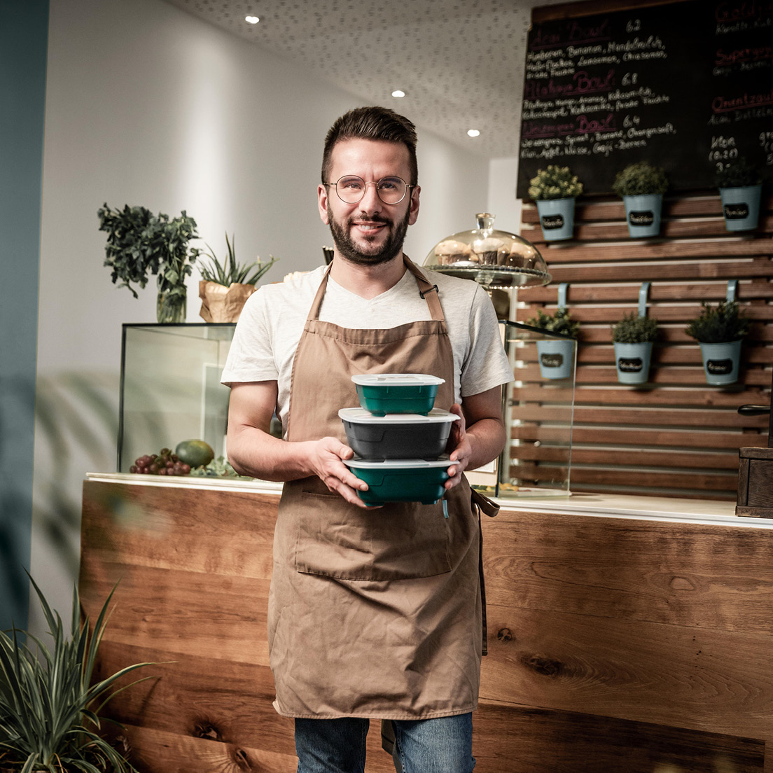 Person bringt To-Go-Ware mit stapelbaren Mehrwegbehältern von thermohauser im Restaurant, 2022.